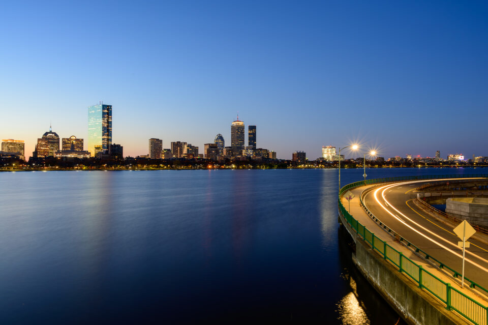 Boston skyline from Longfellow Bridge at sunrise, with the early light casting a blue glow over the city.