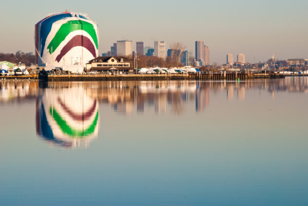 The Rainbow Swash, also known as the Boston gas tank, reflecting in the waters of the ocean.