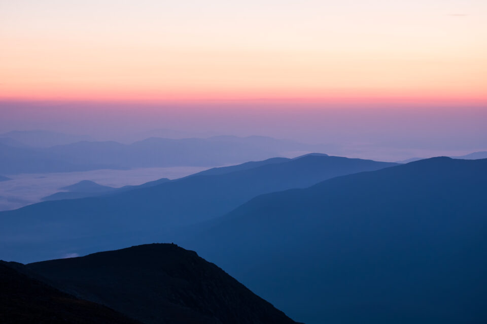 Layers of mountains before sunrise, viewed from the summit of Mount Washington in New Hampshire.