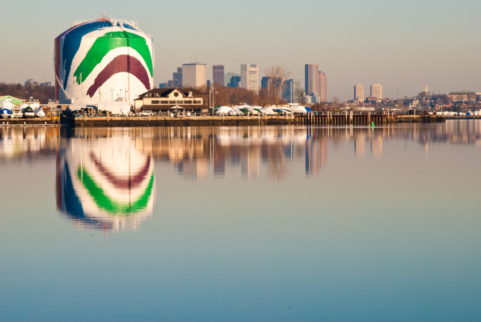 The Rainbow Swash, also known as the Boston gas tank, reflecting in the ocean against the skyline.