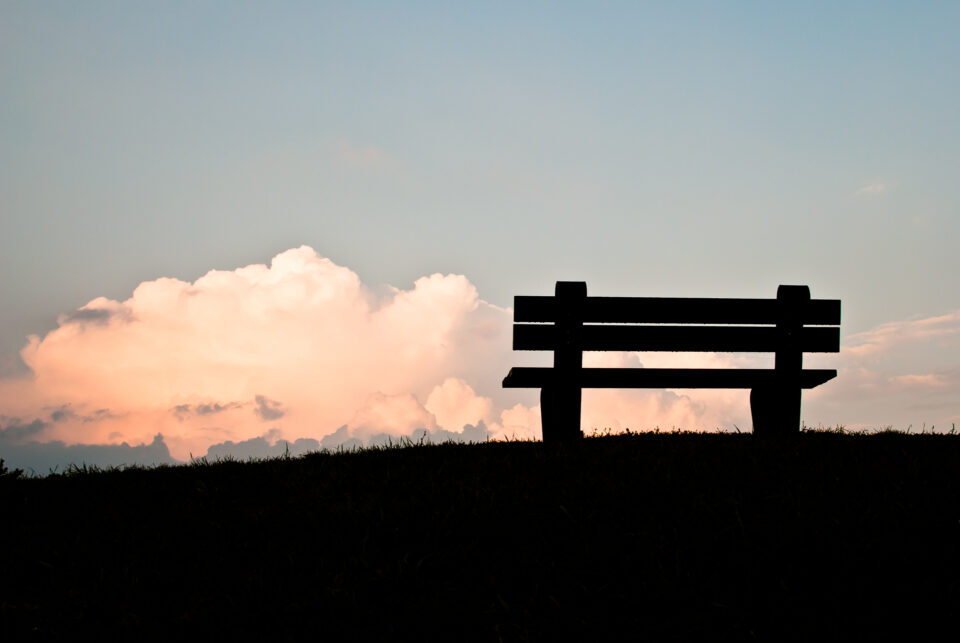 A bench overlooking the sky after sunset, with soft twilight colors filling the horizon.