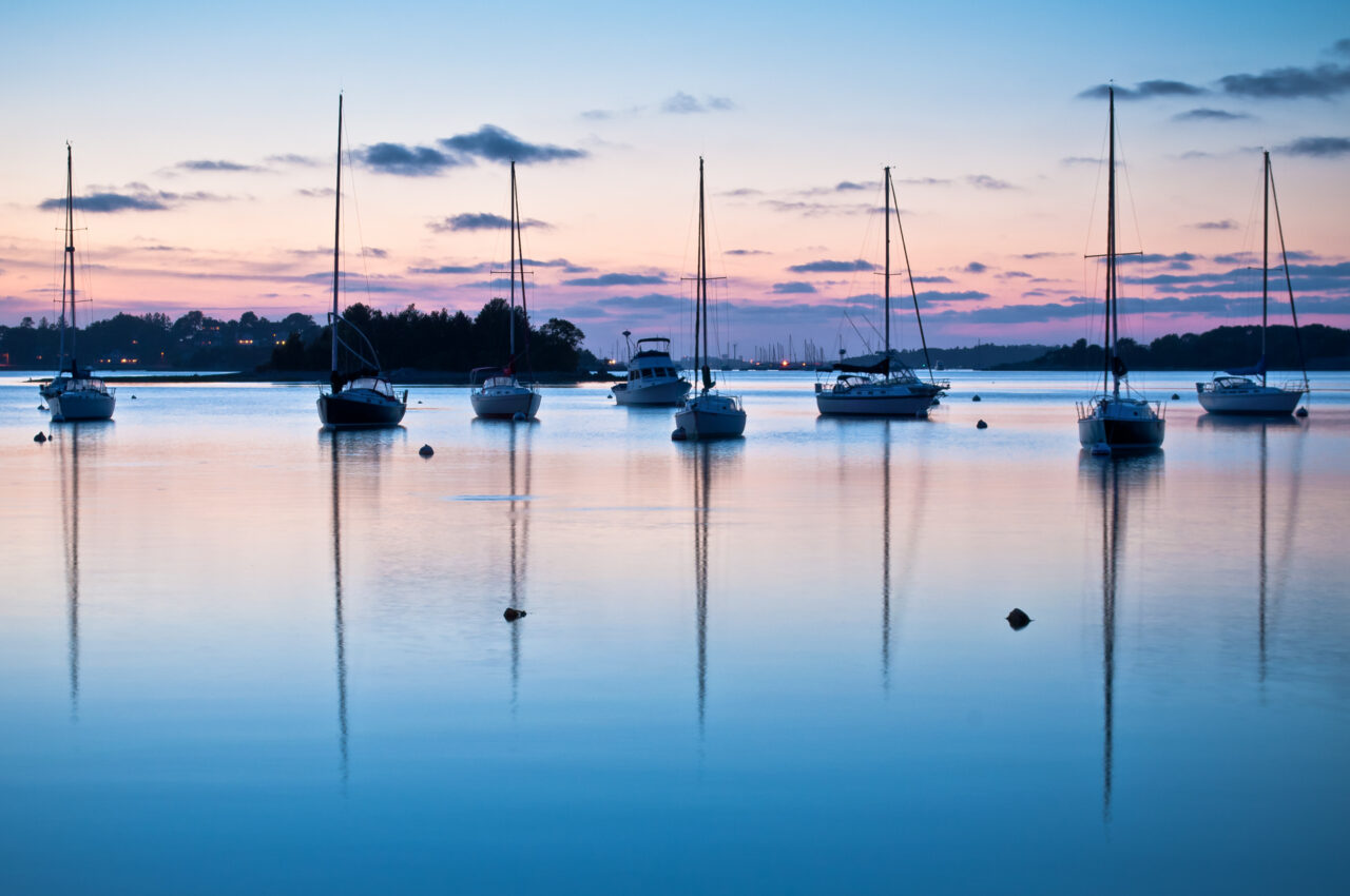 Boats reflecting in the water during sunset over Hingham Harbor.