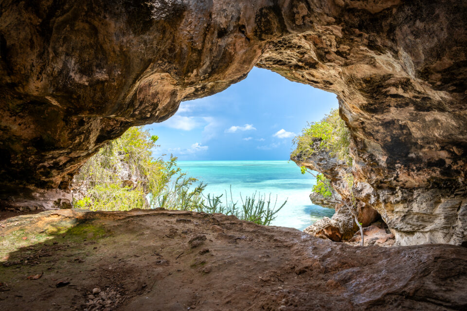 A view from inside Pirates Cove on the island of Turks and Caicos, with turquoise waters and lush surroundings.