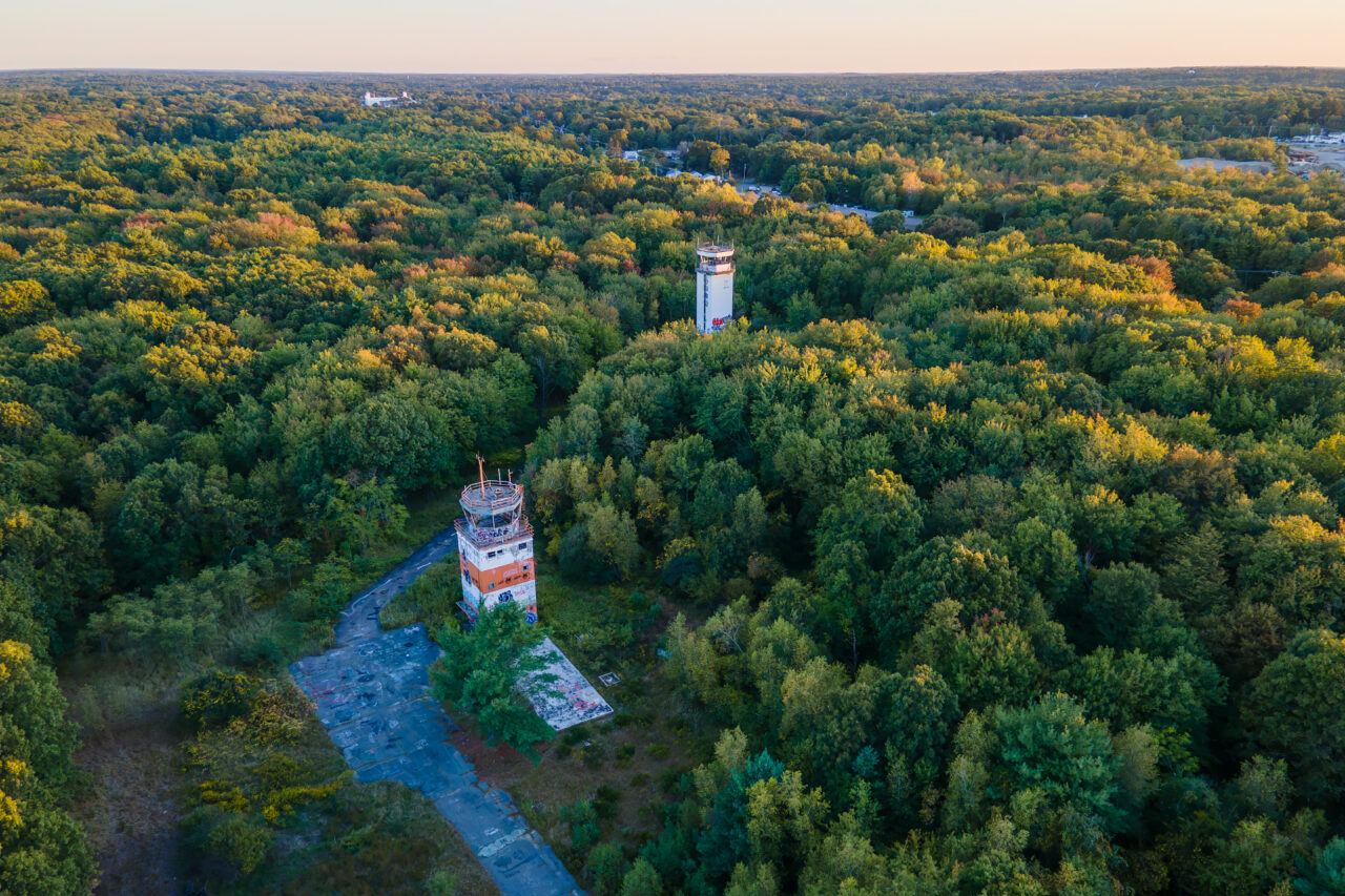 The two abandoned control towers at South Weymouth Naval Air Station rising from a dense forest.