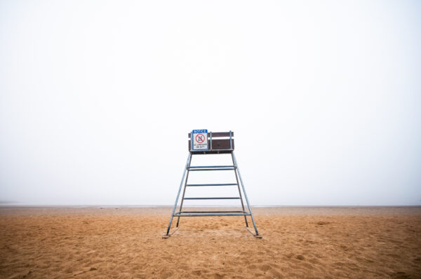 An empty lifeguard chair sits at the Houghton's Pond Recreation Area within the Blue Hills Reservation on a foggy day.