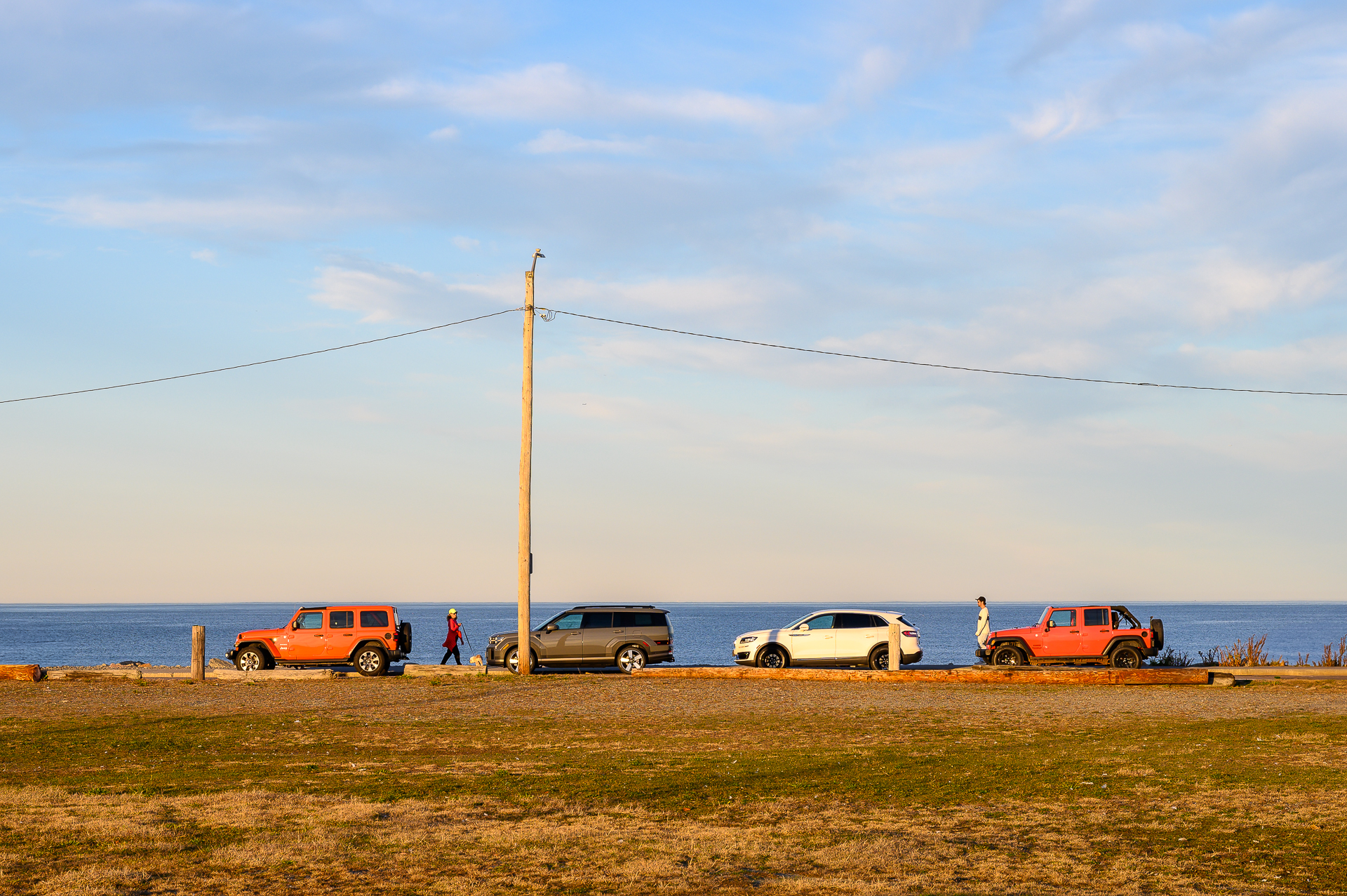 Jeep twins parked by a seawall at the beach.