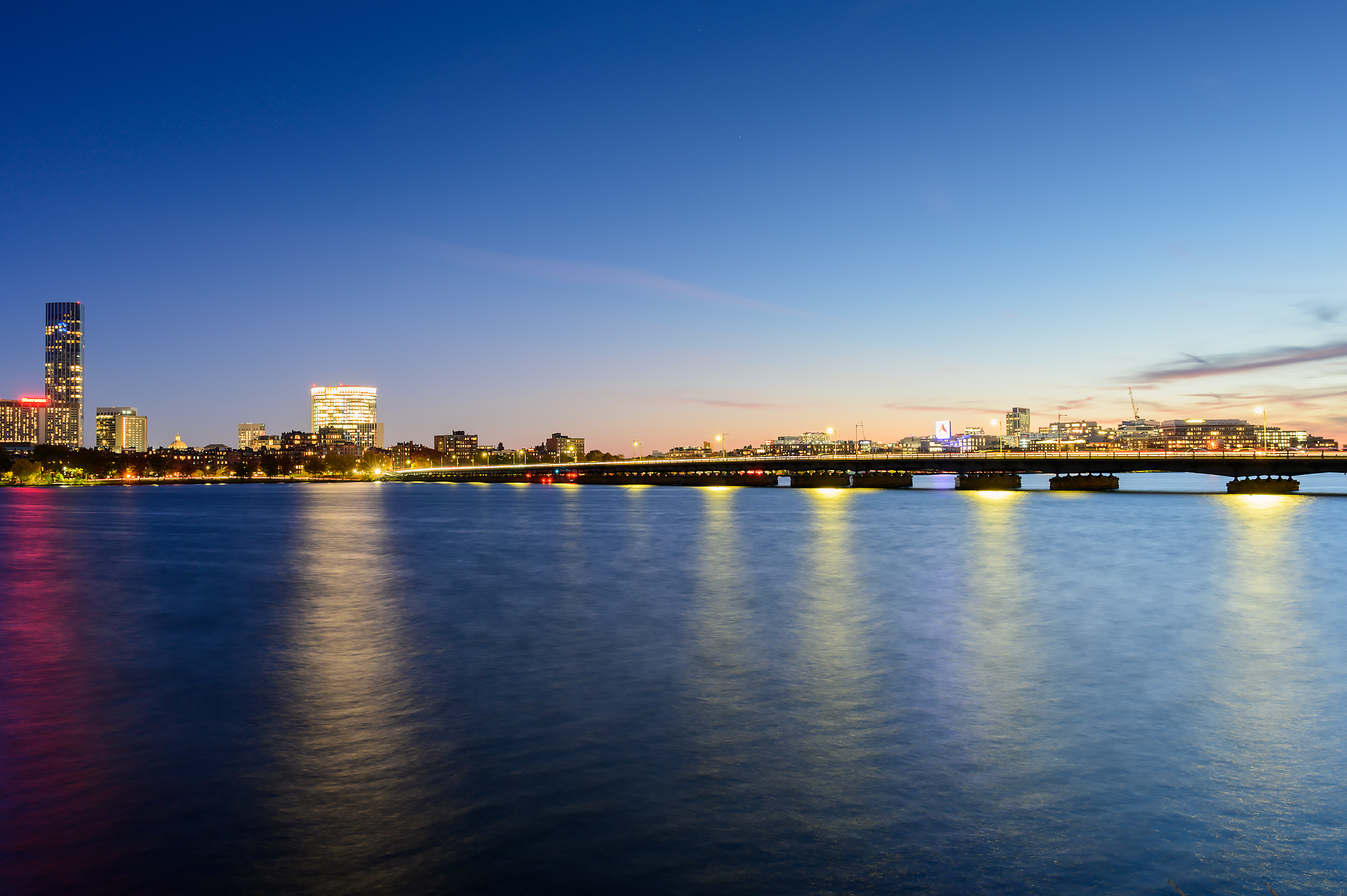 A dusk view of the Harvard Bridge with the Boston skyline in the background.