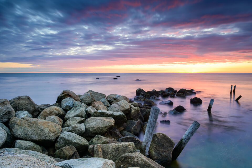 Rocks leading to the ocean during a colorful sunrise at Manomet Point in Plymouth, Massachusetts.