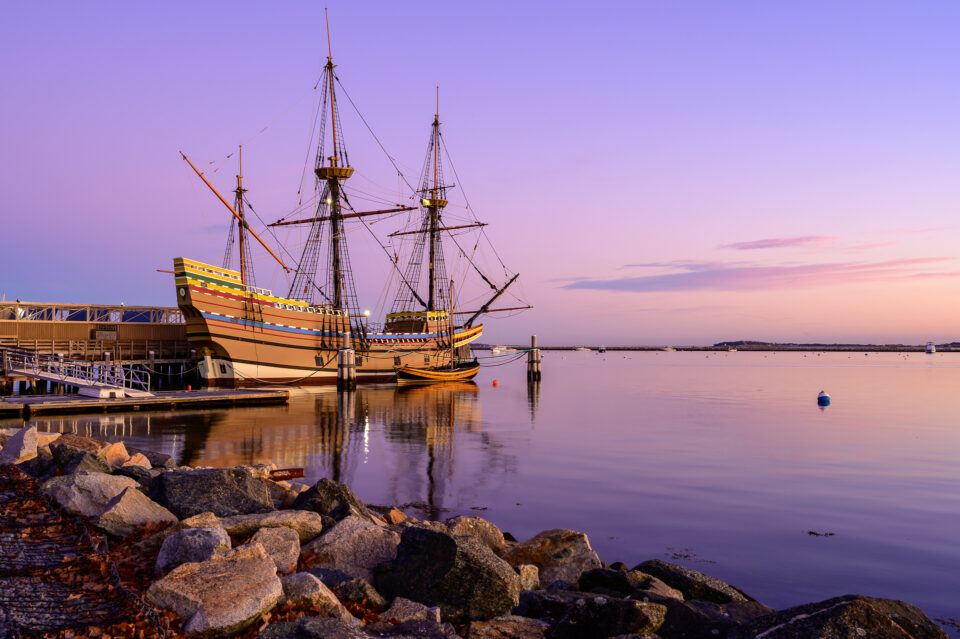 Rocks at the beach leading to The Mayflower II at sunrise in Plymouth, Massachusetts.