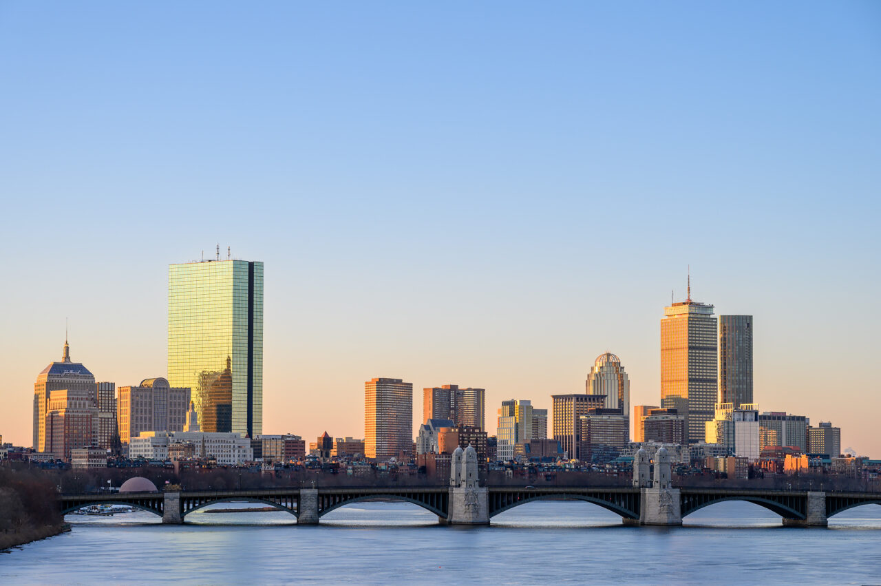 A view of the Boston skyline from a secret spot at sunrise, with the Charles River in the foreground leading toward the Longfellow Bridge and famous landmarks in the background.