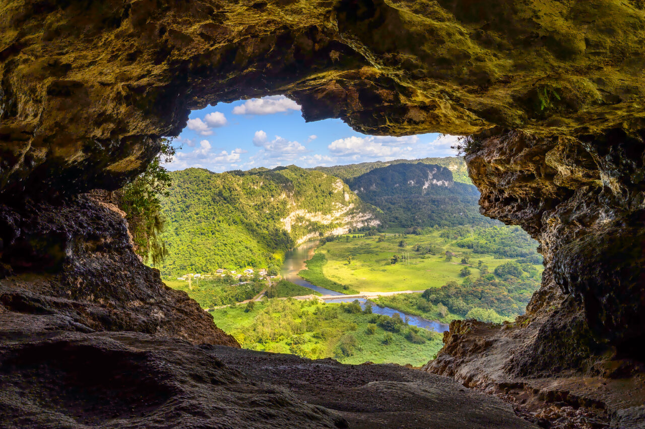 View from inside Cueva Ventana in Puerto Rico, looking out over the lush green Río Grande de Arecibo valley through the cave’s natural window opening.