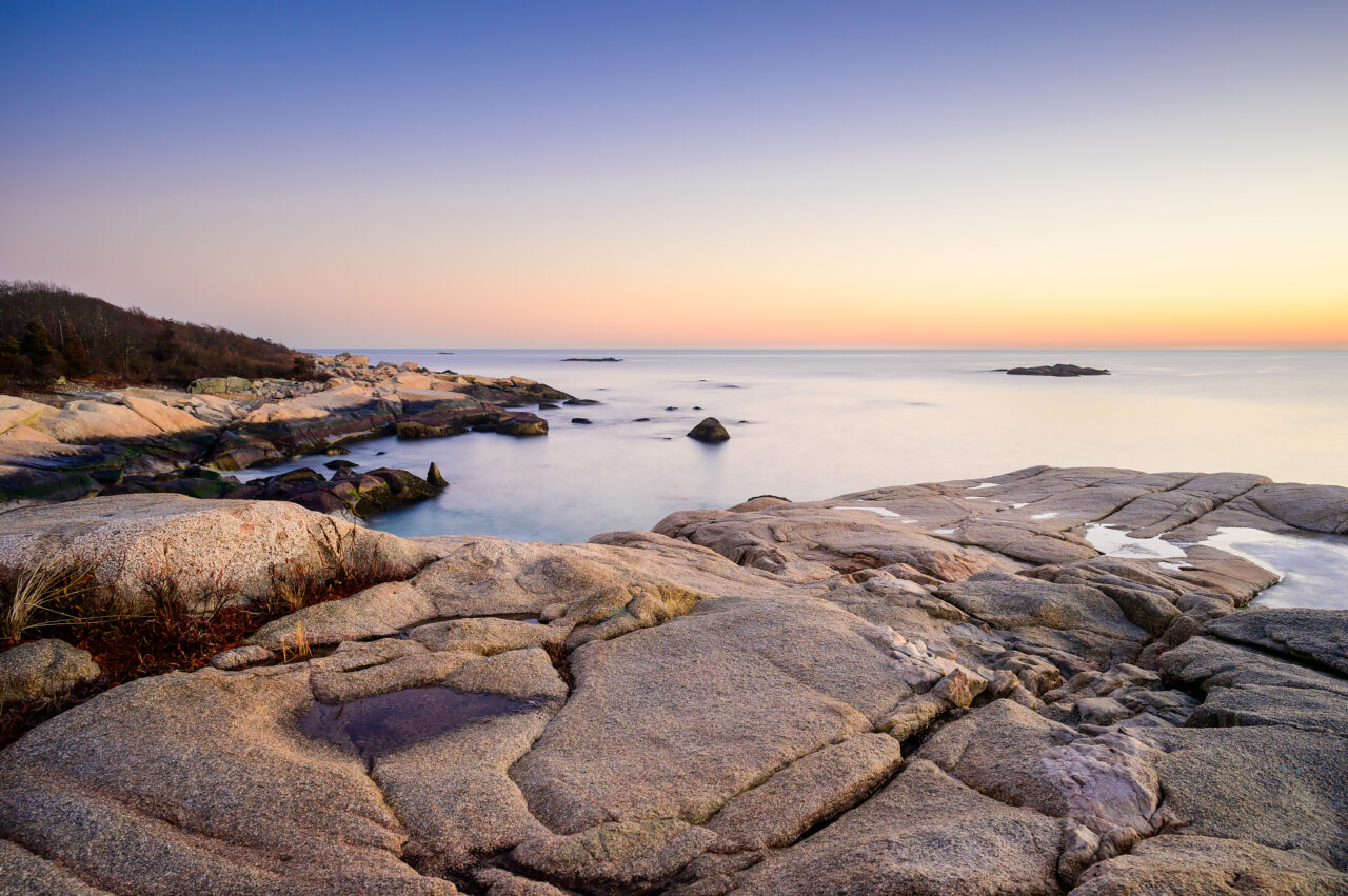 A cliff overlooking the ocean horizon at Scituate Neck during sunrise.