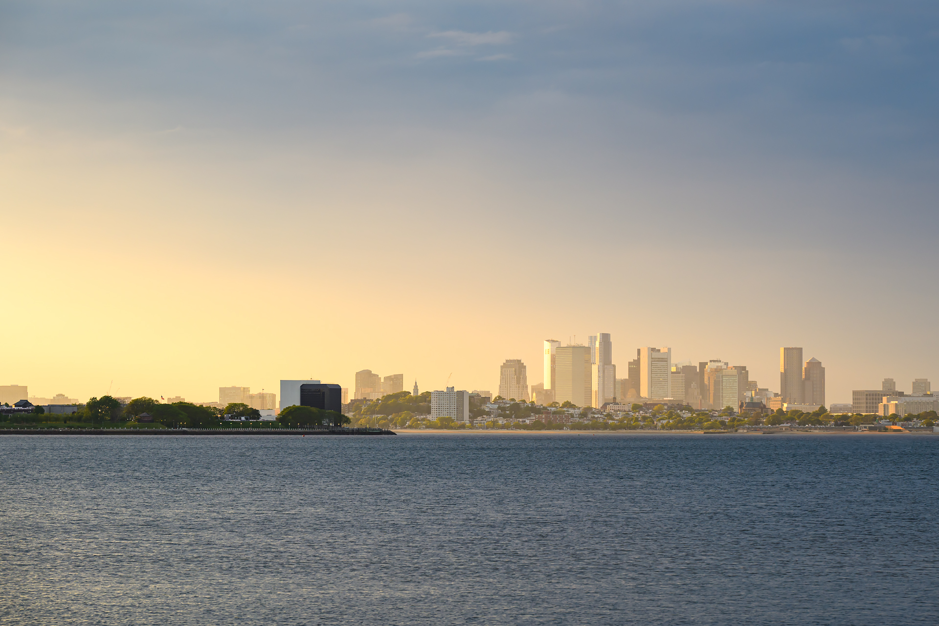 View from Squantum in Quincy, looking north across the bay toward Boston, illuminated by the warm light of golden hour.
