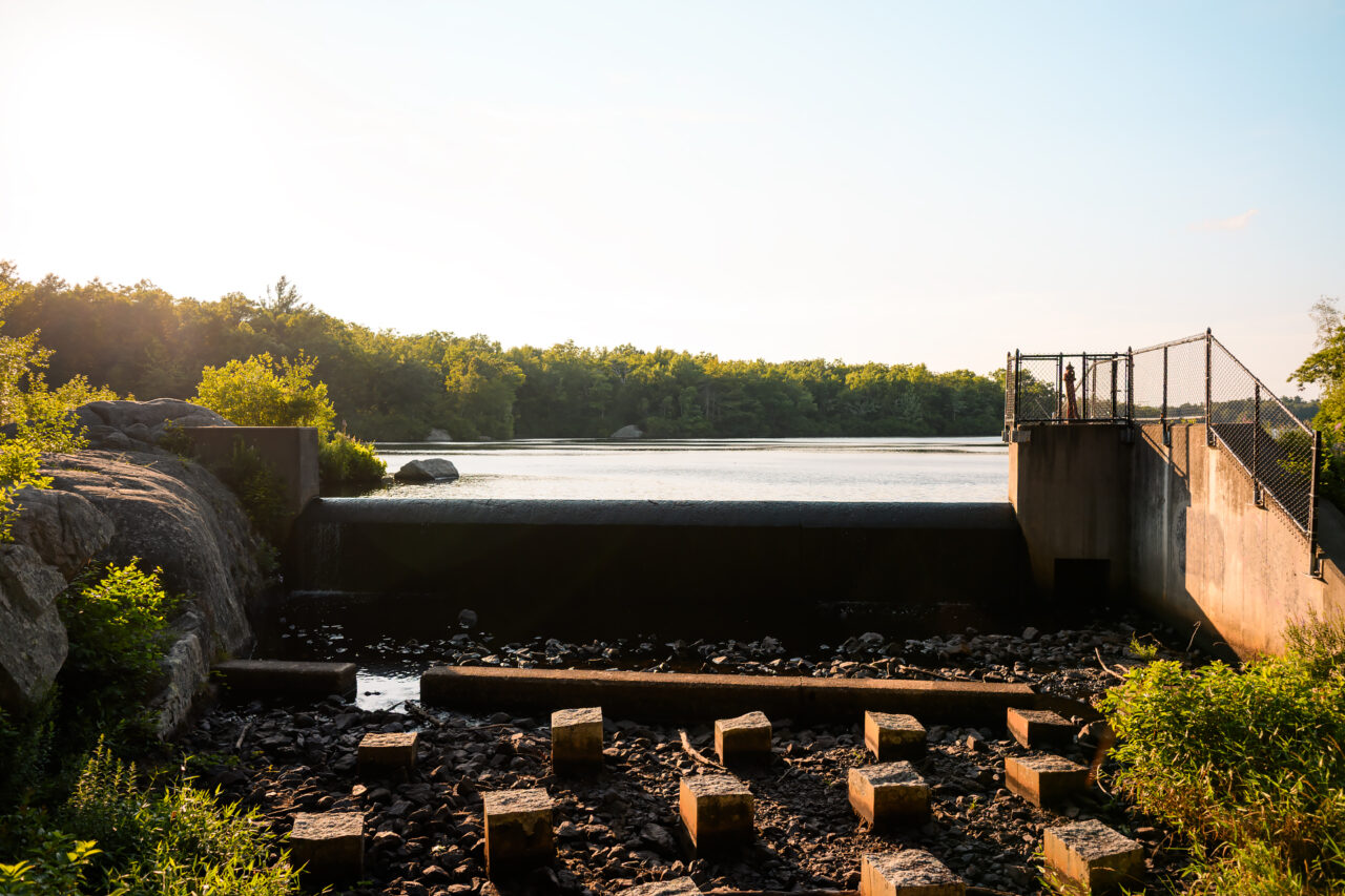 Golden hour light illuminates the spillway at Cleveland Pond within Ames Nowell State Park, Abington MA.