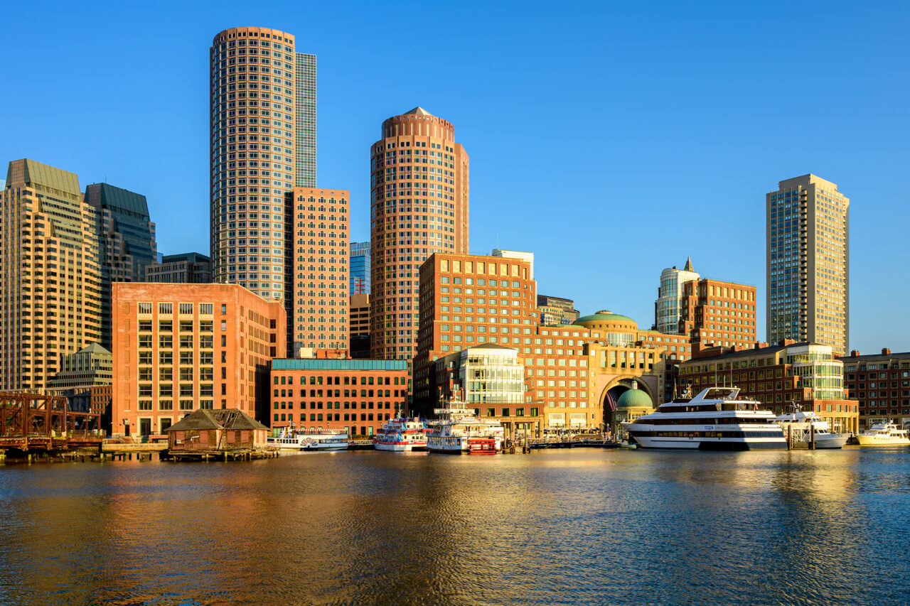 Boston Harbor Hotel and waterfront at Rowes Wharf reflected in calm morning water.