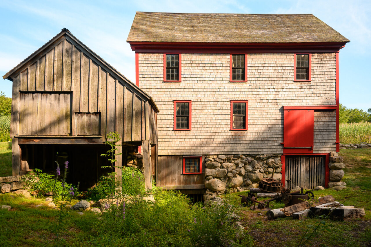 Exterior view of Hatch Mill in Marshfield, Massachusetts, showing the main mill building and picnic tables on the grassy grounds.