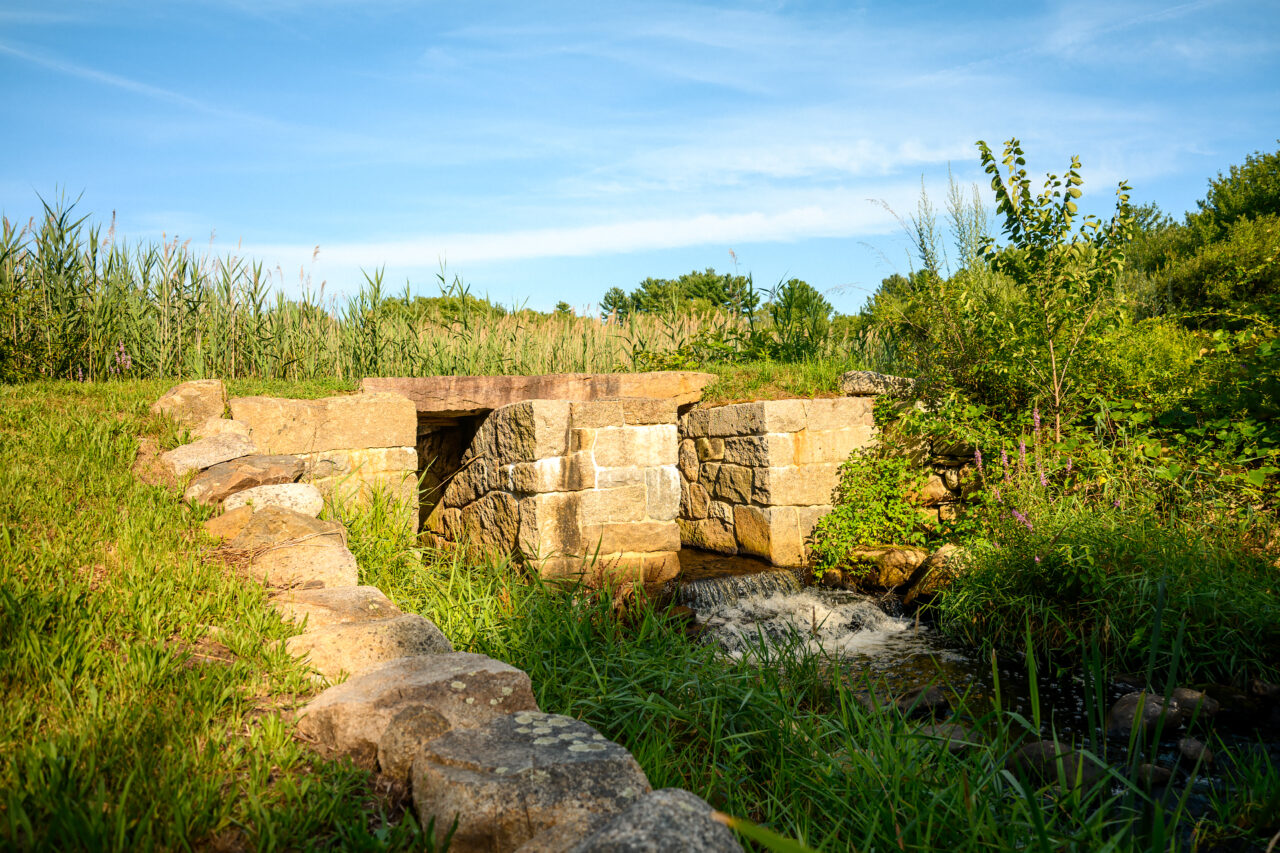 Stone culvert and flowing water of Two Mile Brook at Hatch Mill in Marshfield, MA.