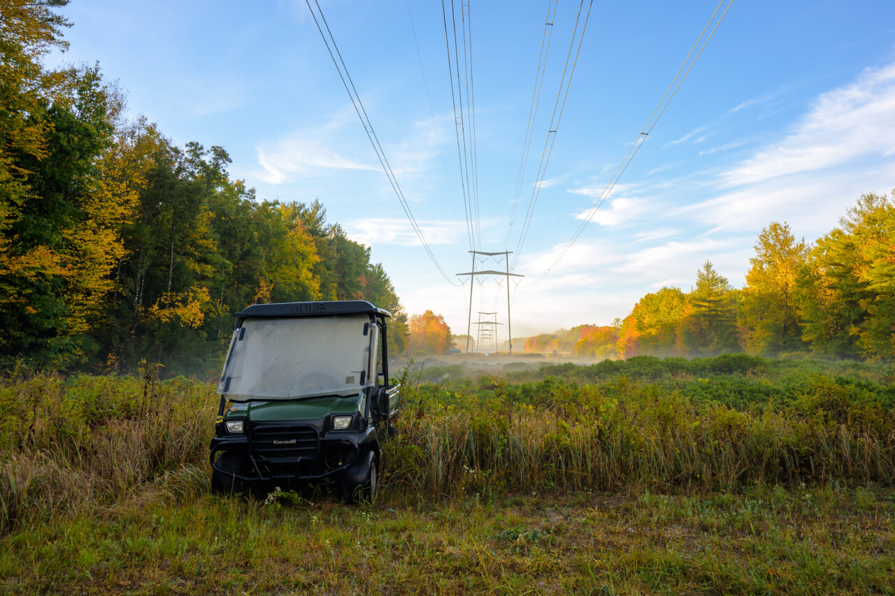 A utility vehicle is seen parked near receding power pylons in a foggy autumn field in Holbrook, Massachusetts.