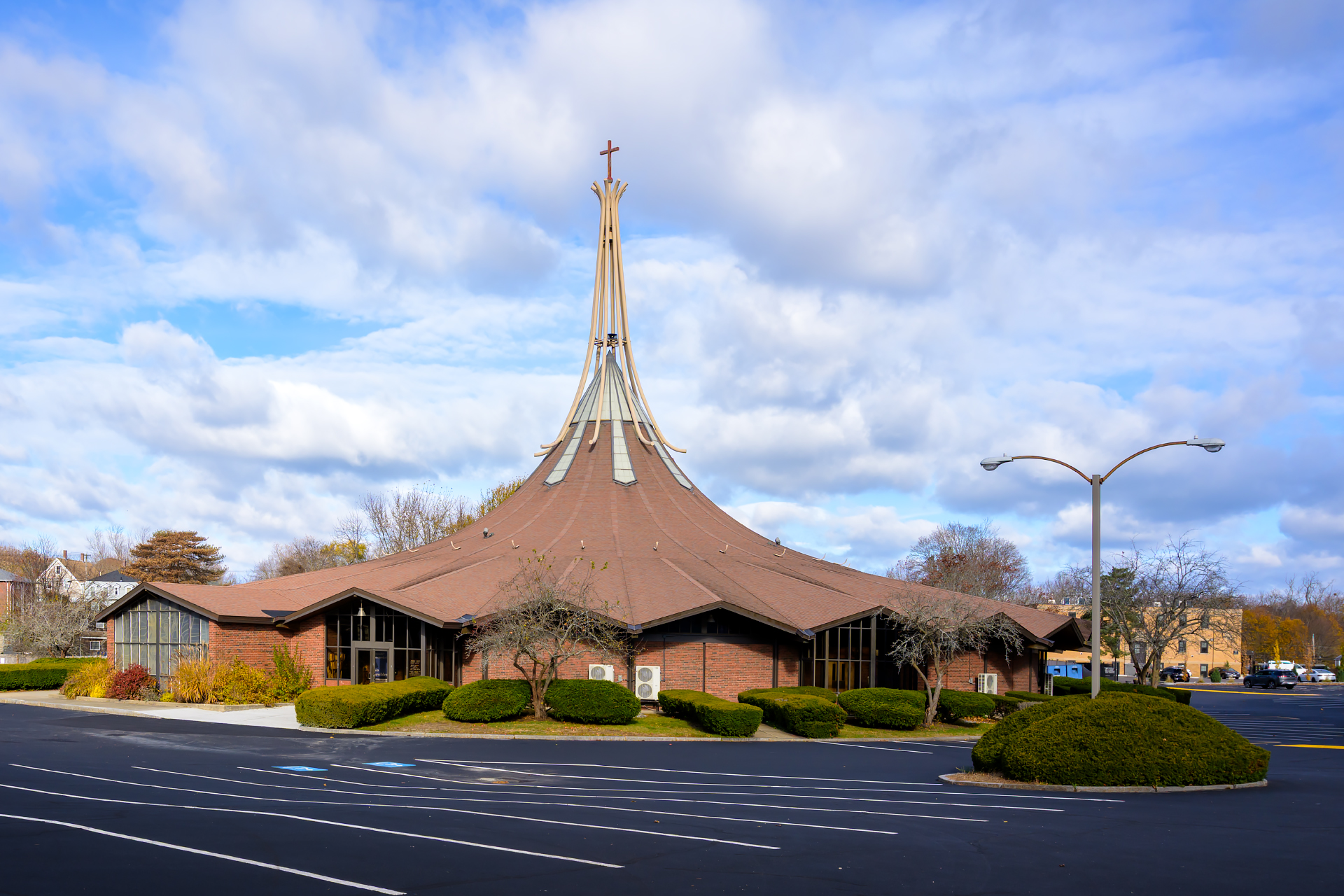 Immaculate Conception Parish in Weymouth, Massachusetts, its tapered spire set against a cloudy sky.
