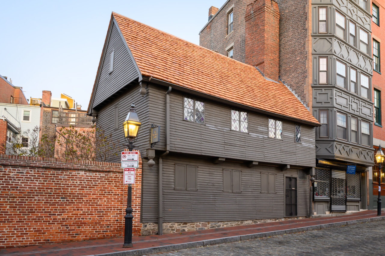 Side view of the Paul Revere House next to a modern, tall brick building.