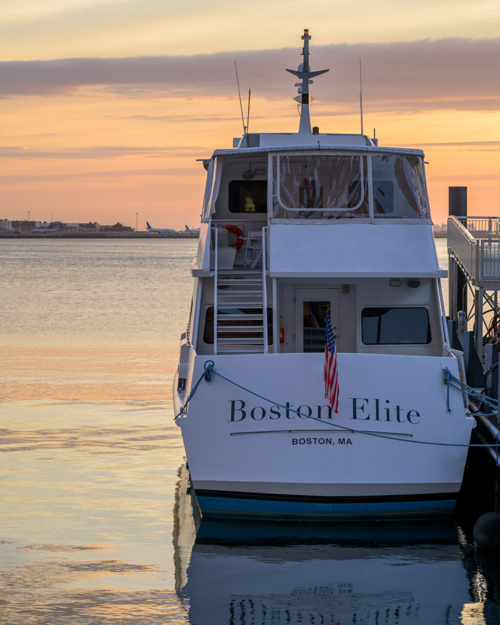 The Boston Elite boat docked in the harbor during a golden winter solstice sunrise.