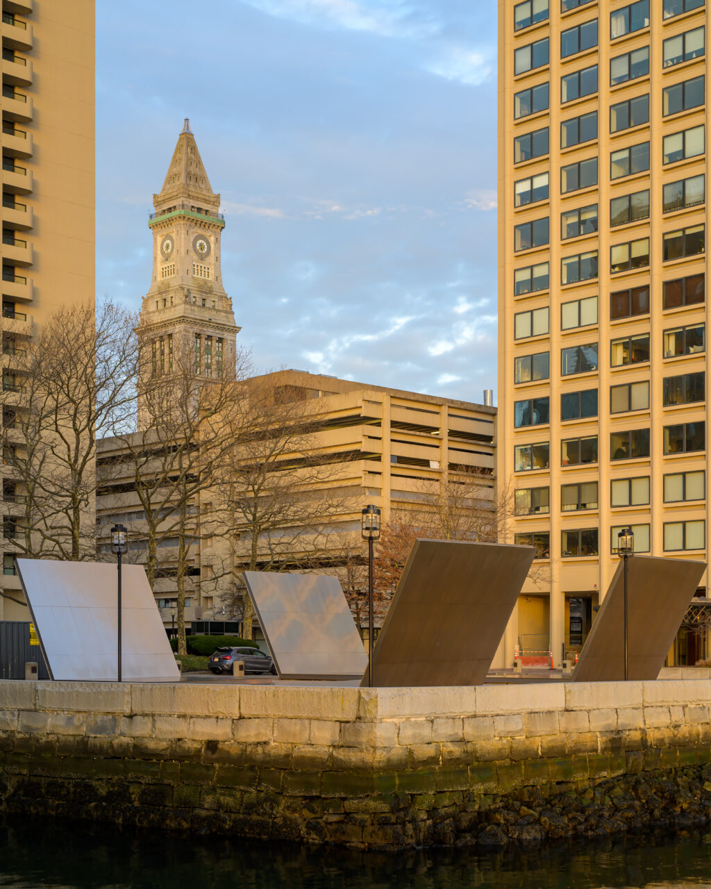 The historic Custom House Tower framed by modern architecture during the morning solstice light.