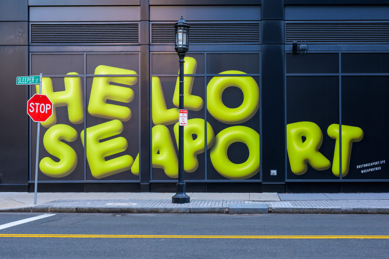 The 'Hello Seaport' sign and Sleeper Street stop sign in Boston's Seaport District during a quiet winter morning.
