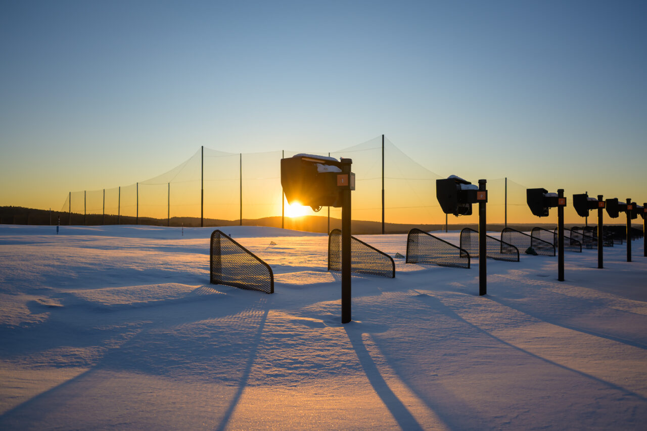 The sun peeking through silhouetted hitting bays at Granite Links, casting long winter shadows across the deep snow.