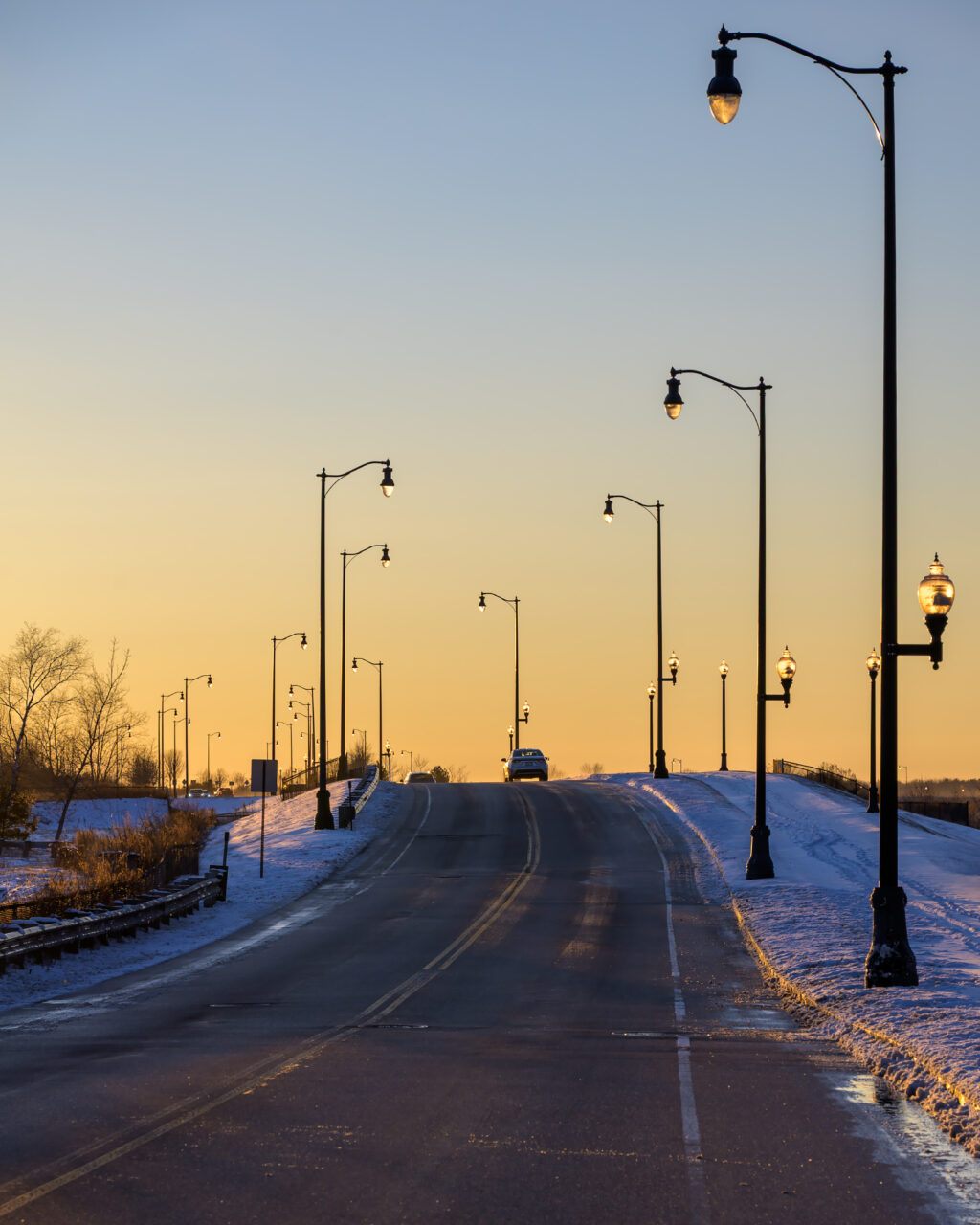 A car heads west on Bill Delahunt Parkway during golden hour at the former South Weymouth Naval Air Station.