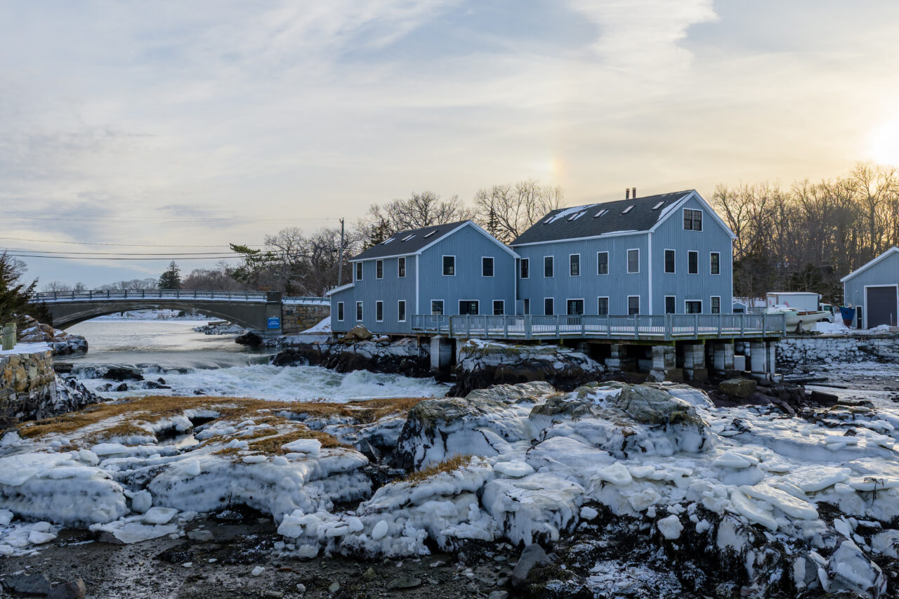 Fast-moving water rushes past a frozen rocky cliff at the Cohasset Lobster Pound in Cohasset, Massachusetts.
