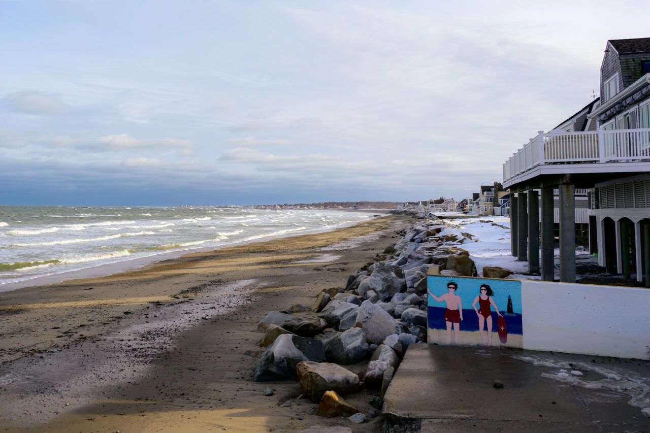 A painted mural of two lifeguards on a concrete wall at North Scituate Beach.