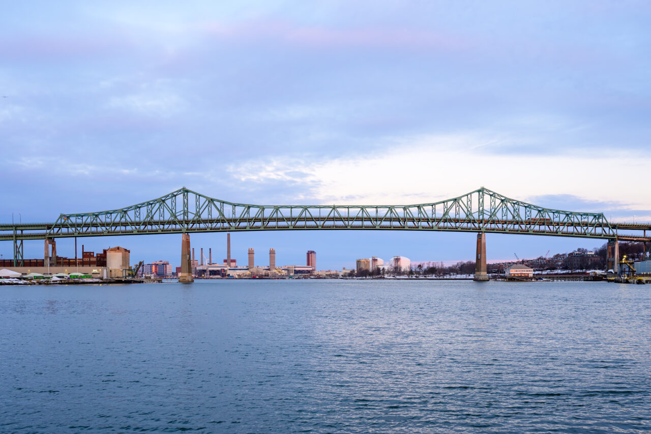 The green Tobin Bridge spanning the water under a soft East Boston sunrise.