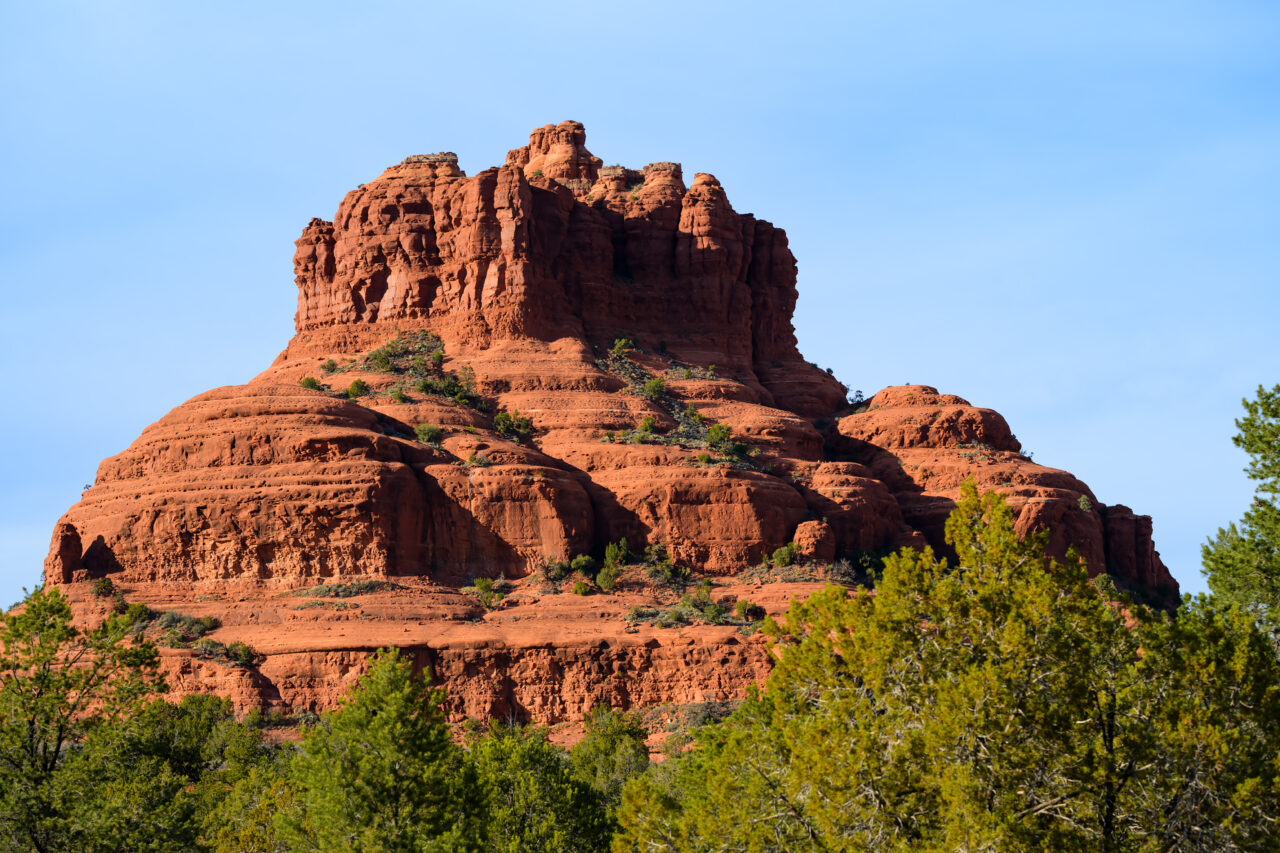 A close-up view of Bell Rock in Sedona glowing under a clear morning sky.