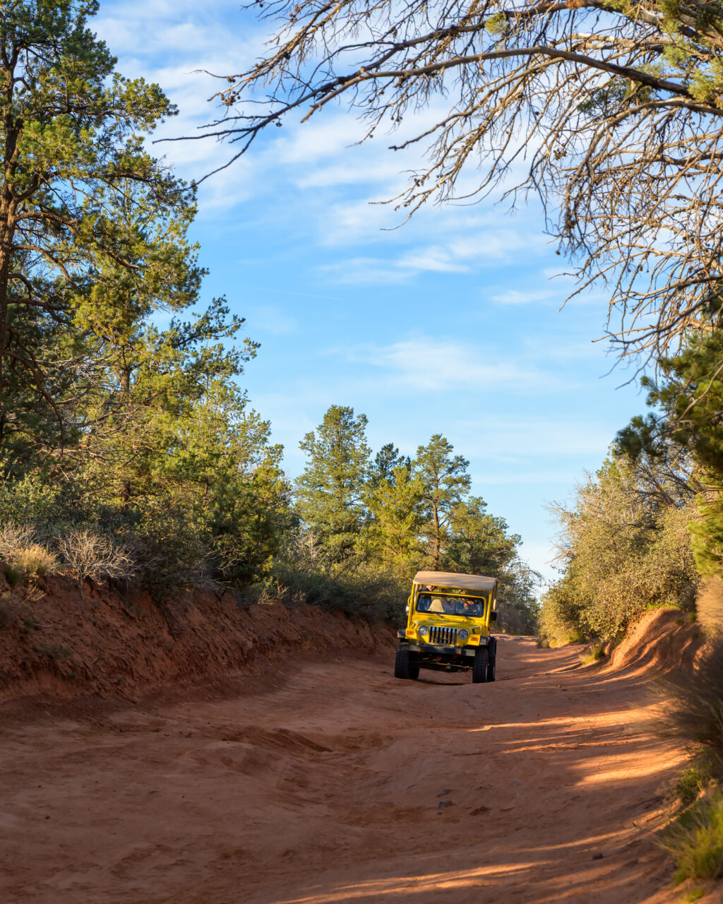 Yellow Jeep driving along Dry Creek Road toward Devil’s Bridge in Sedona, Arizona.