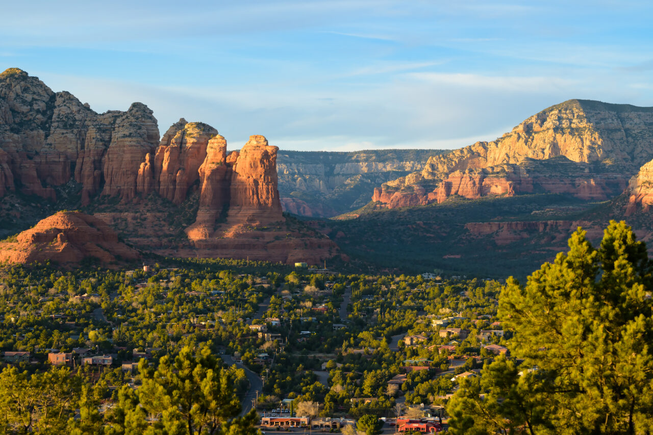 A golden sunset glow over the valley and red rock formations seen from Airport Mesa in Sedona.