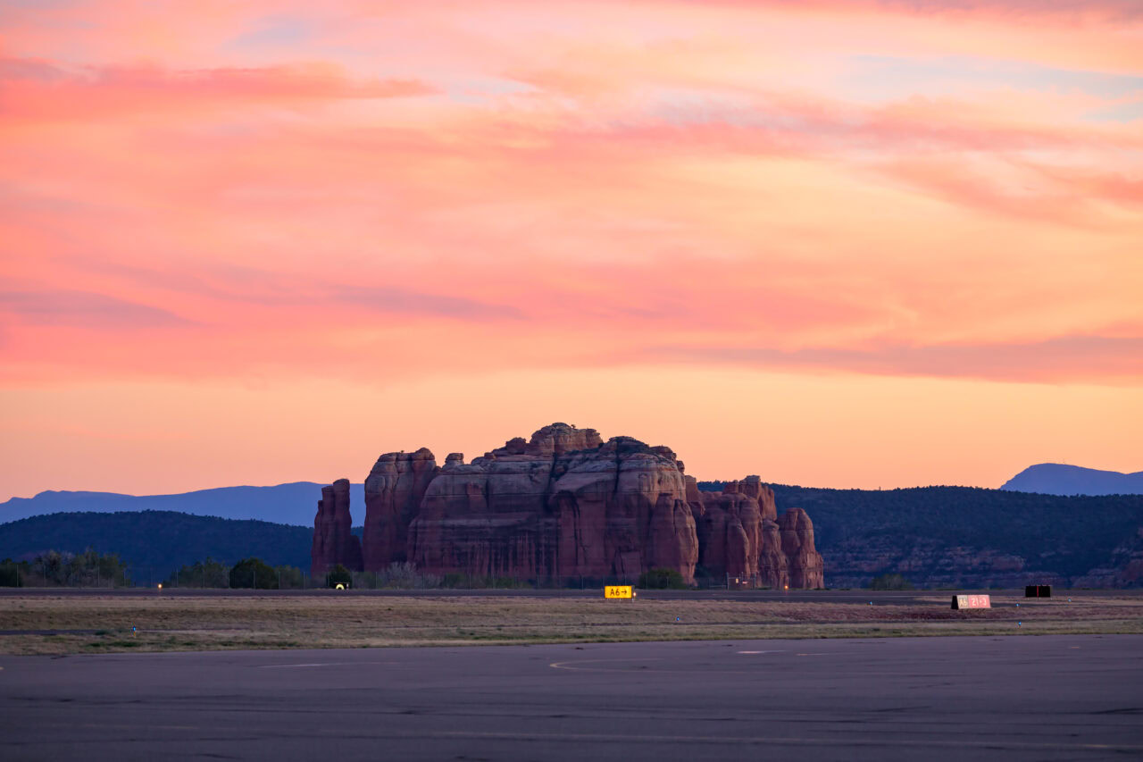 The red rock formation under a pink sky, viewed from the Sedona Airport runway.