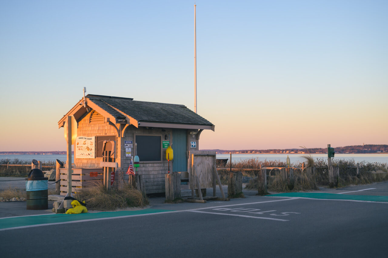 Weathered beach shack at Duxbury Beach in soft pink and orange sunrise light.