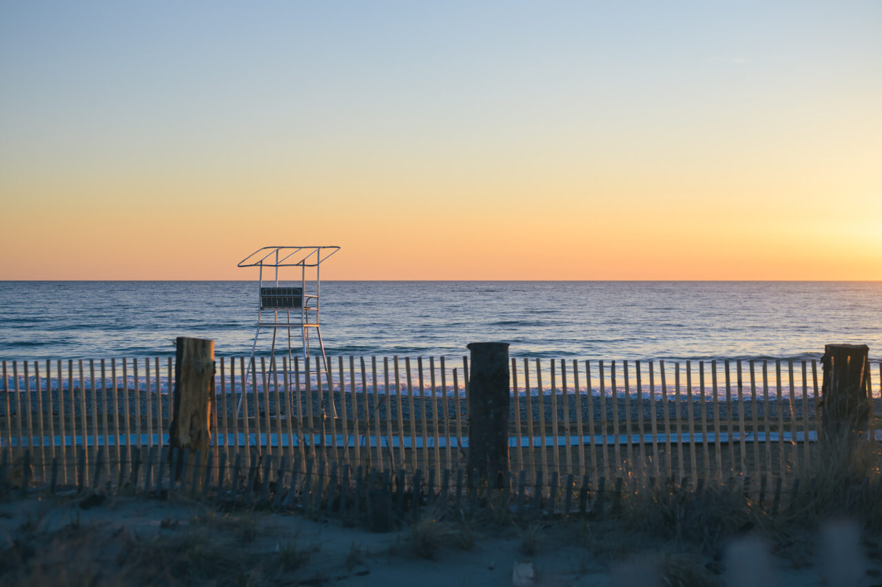 Empty lifeguard stand at Duxbury Beach behind snow fencing before sunrise.