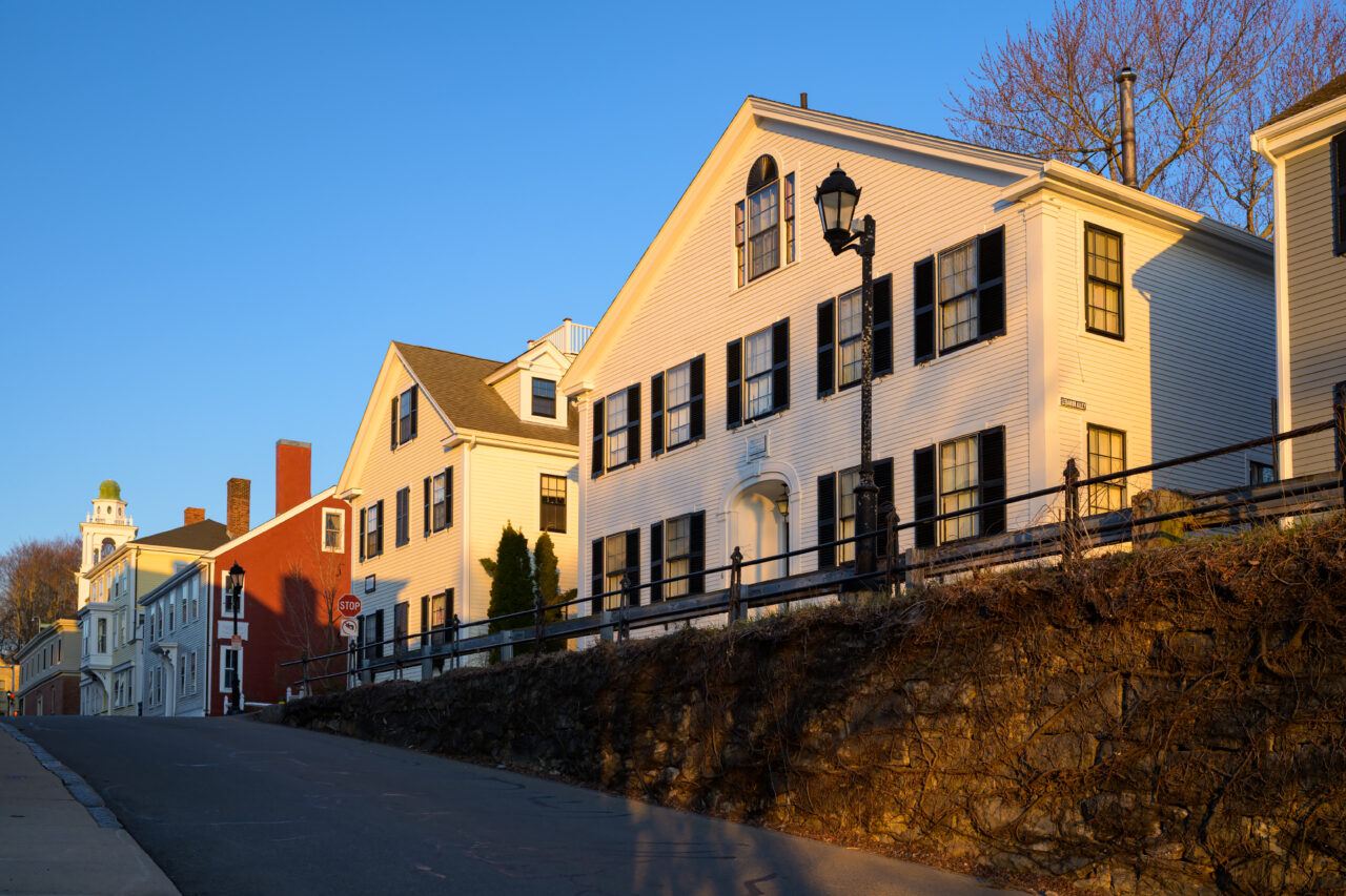 Colorful historic houses along Leyden Street in Plymouth lit by warm early morning sunlight.