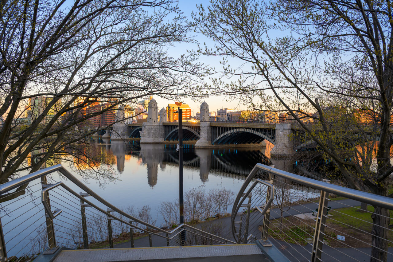 Staircase descending toward the Charles River with the Longfellow Bridge in the background at sunrise.