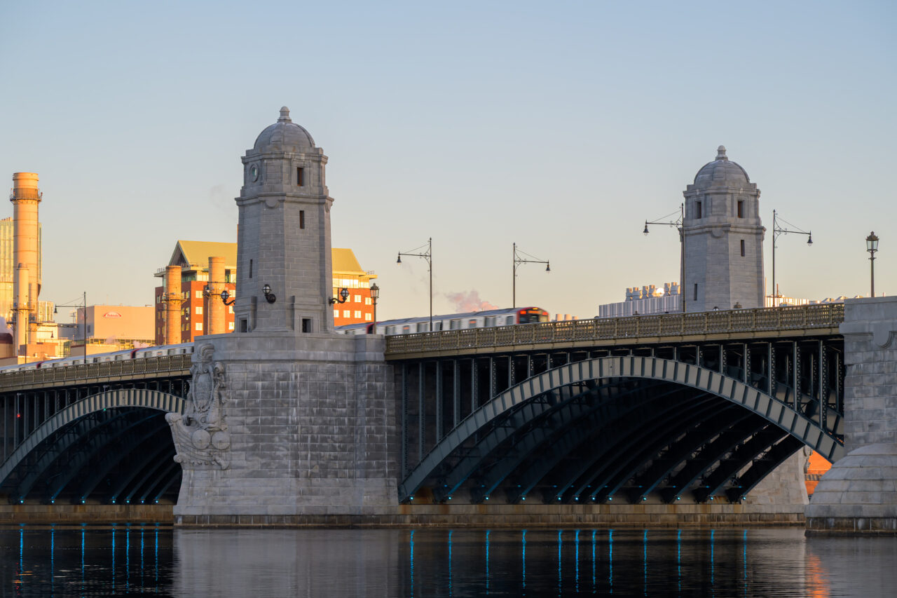 Red Line train crossing the Longfellow Bridge between the granite towers at sunrise.