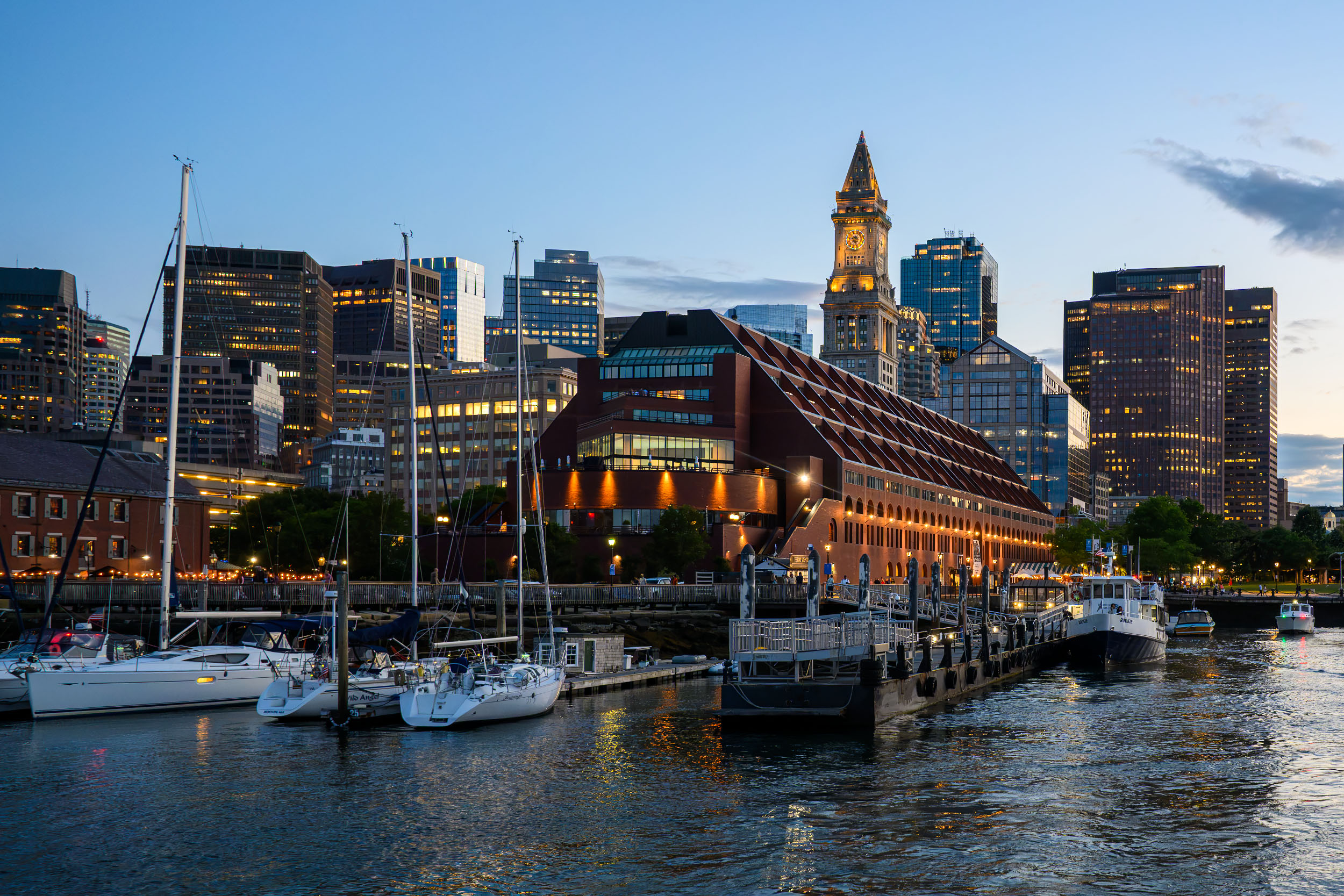 Boston harbor at blue hour with Custom House Tower and sailboats at Long Wharf.