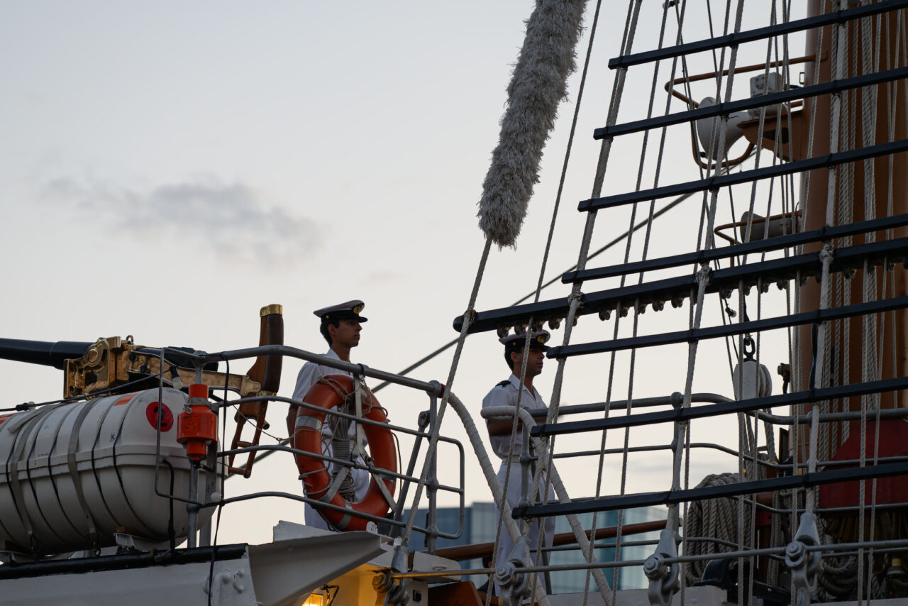 Officers standing on deck aboard Portugal's Sagres at dusk.